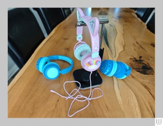 3 different pairs of colorful headphones one pair hanging from a silver stand and with cat ears attached to the headband