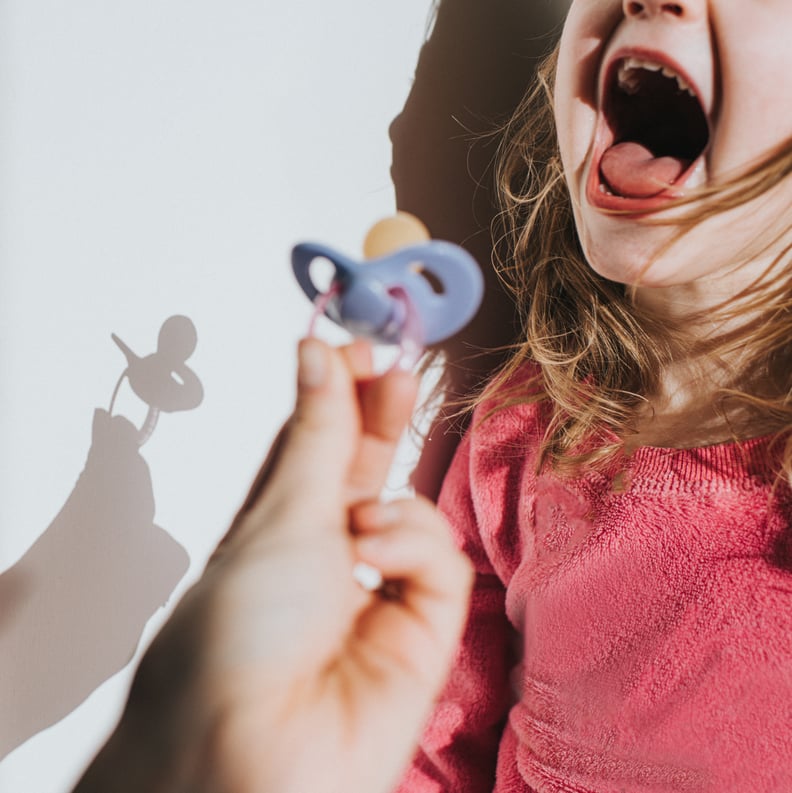 Parent taking / giving a young girl a purple dummy