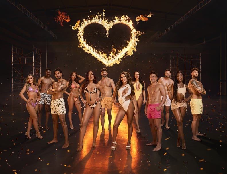 Pictured are the Love Island 2024 cast, they're all wearing swimwear and stand in front of a heart on fire. From left to right: Samantha, Ayo, Munveer, Nicole, Patsy, Ciaran, Harriet, Jess, Sean, Ronnie, Mimii, Sam 