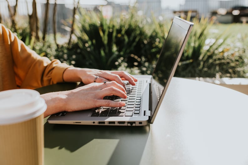 Corporate image of hands typing on a laptop keyboard in an outdoor environment, perhaps a balcony, a garden or a rooftop terrace.