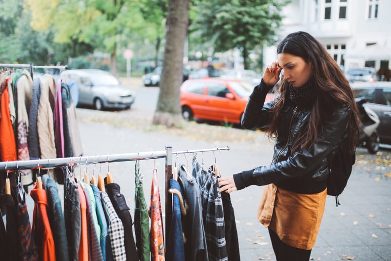 Vintage toned portrait of a young woman in Berlin, wearing a black leather jacket and a beige skirt, walking down the street in Berlin  Kreuzberg district in the late Autumn day, shopping on the street market. Street style, casual fashion concept.