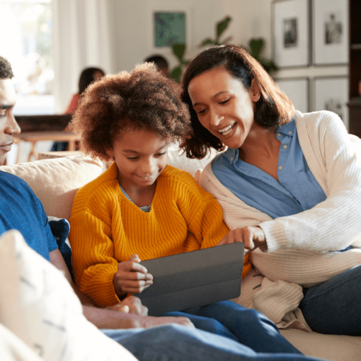 Parents looking over their child's shoulder while using an iPad.