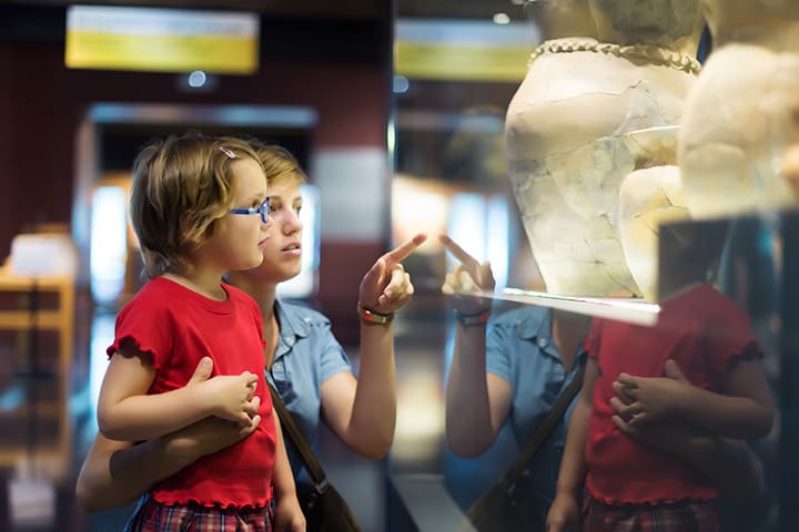 A mother and child look at an exhibit at the Bothell Historical Museum. The items in the case are hard to define.