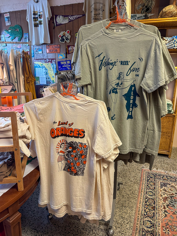 5801 Print House Brings Vintage Florida Designs To St. Pete - T shirts hanging inside the print shop with vintage style logos on them.
