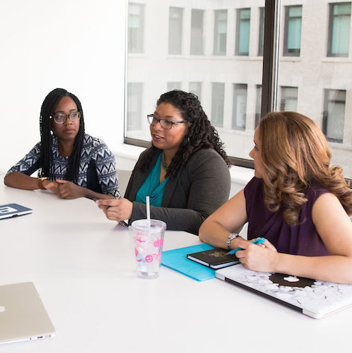 Three women sitting and having a meeting at a conference table in a corporate setting