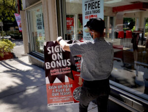 a fast-food employee sets up a help wanted sign