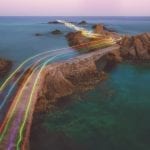 Lenovo brand image showing rainbow streaks flying over rocky islands at sea.