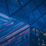 brand image - Evening shot of cars shot in slow motion creating red lighting blurs below blue glass building.