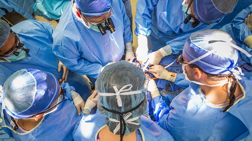 surgeons in blue surgical gowns performing a transplant