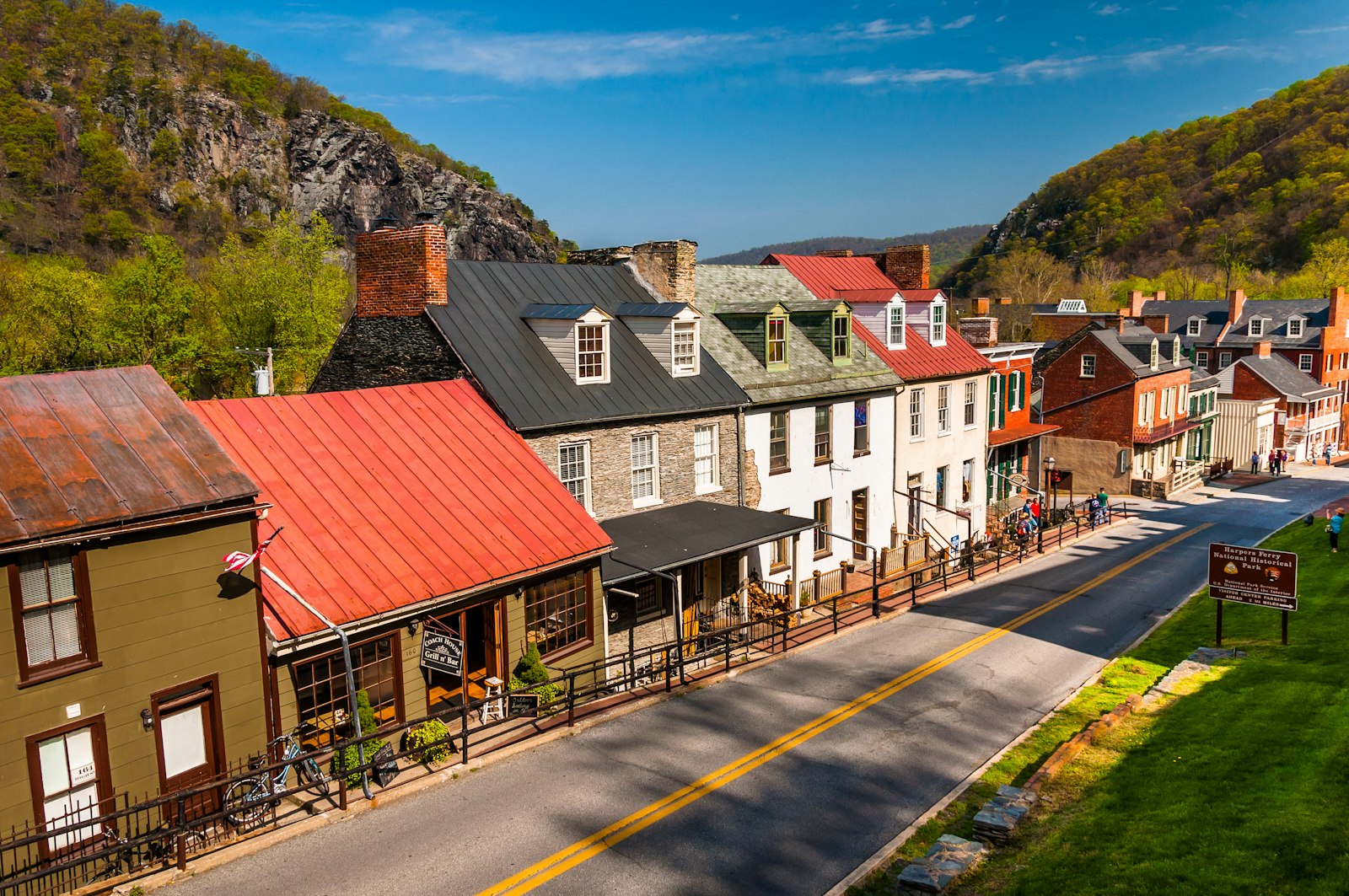 A street lined with closely set buildings. In the distance are rolling mountains.