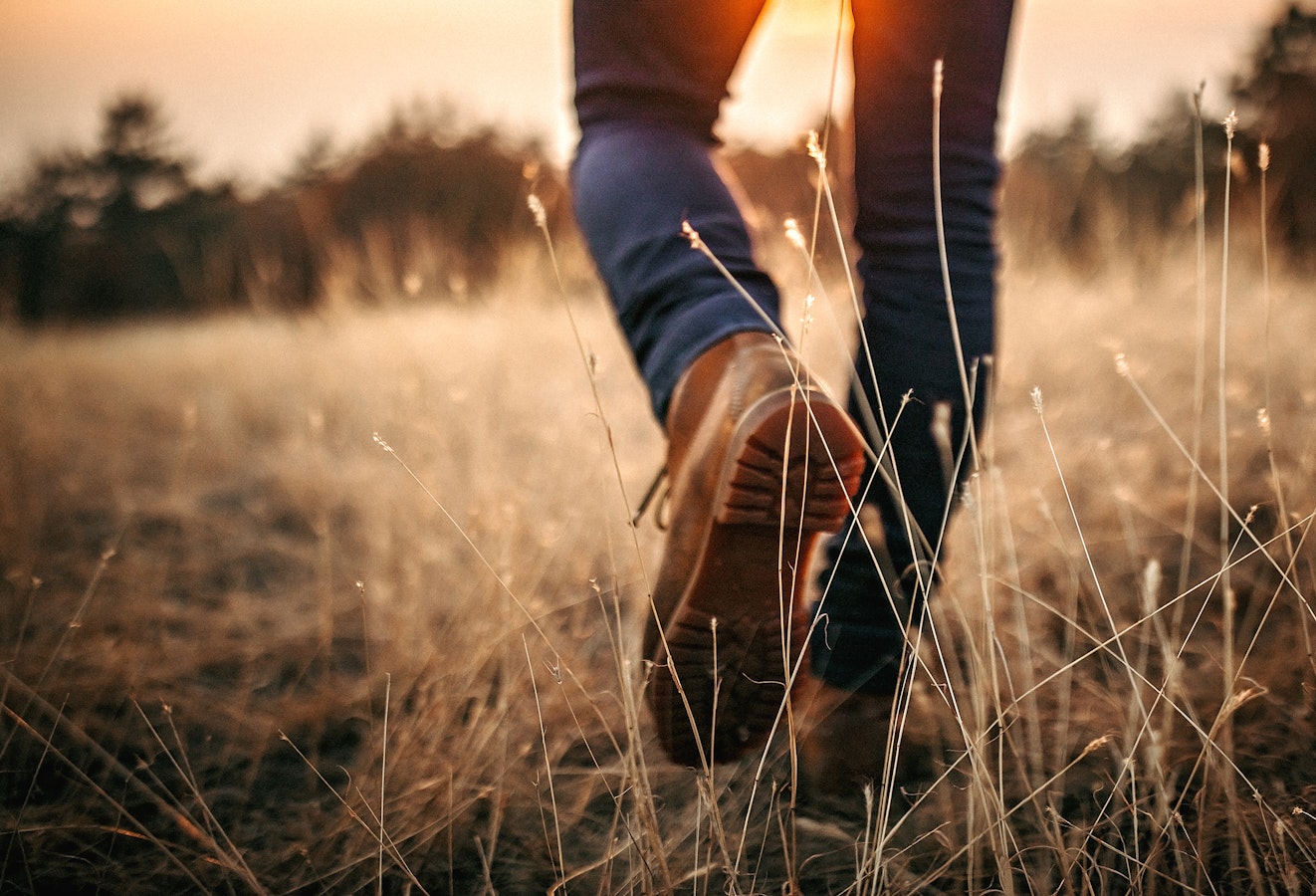 A person wearing boots walks through a field