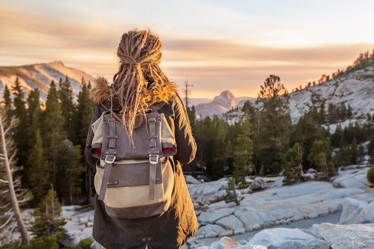 A person looks into the distance over a mountainous landscape at sunset