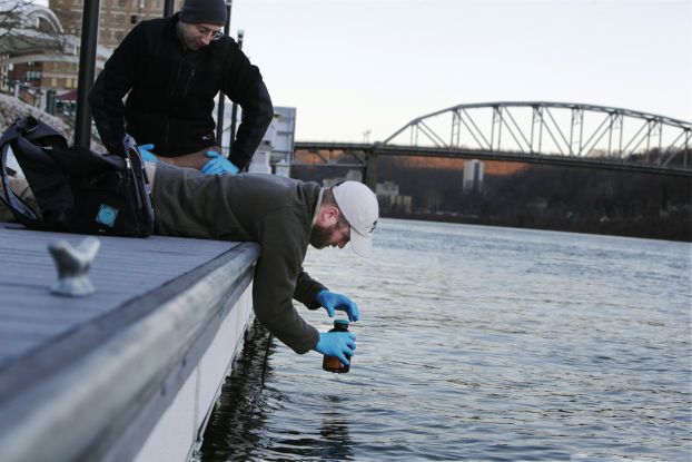 A researcher collects a water sample from a river