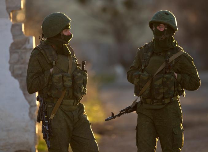 Pro-Russian soldiers stand close to the main gate of an Ukrainian military base in Perevalne, Ukraine, Saturday, March 15, 2014.