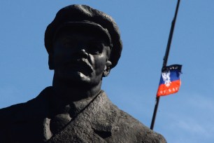 Donetsk People's Republic flutters behind a statue Vladimir Lenin