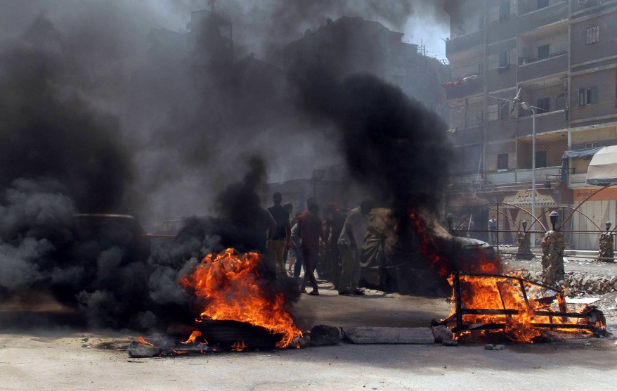 Protesters, supporters of the Muslim Brotherhood, are seen behind burning tires during a protest in the Matariya area in Cairo, August 14, 2014. Security was tightened on Thursday, which was the one-year anniversary of the clearing of the Muslim Brotherhood sit-in at Cairo's Rabaa al-Adawiya, where at least 817 protesters were killed when security forces stormed two protest. REUTERS/Al Youm Al Saabi Newspaper (EGYPT - Tags: CIVIL UNREST POLITICS TPX IMAGES OF THE DAY) EGYPT OUT. NO COMMERCIAL OR EDITORIAL SALES IN EGYPT