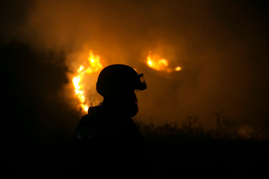 Israeli fire-fighter works to extinguish a fire caused by rockets launched from the Gaza Strip towards Israel near the town of Sderot