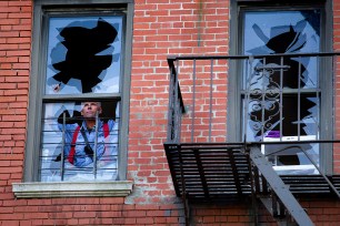 A member of the FDNY looks out a broken window at the scene of the four-alarm fire in Hamilton Heights Monday.