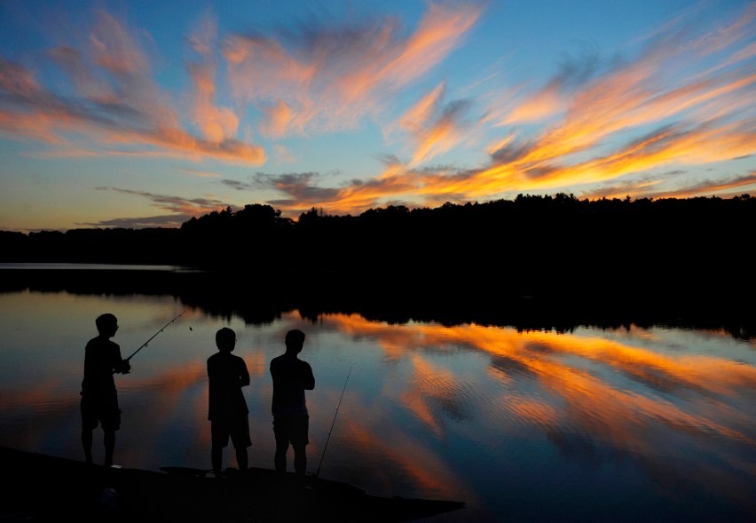 UConn students from Storrs, Conn., Gary Tu, Danny Wang and Victor Zheng, fish at Shenipsit Lake in Tolland, Conn. during sunset on Tuesday, Aug. 19, 2014. (AP Photo/Journal Inquirer, Jim Michaud)