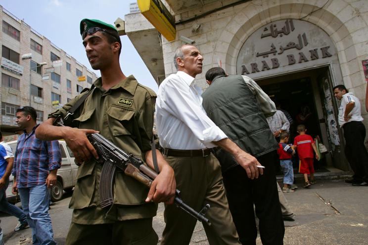 A Palestinian policeman stands guard outside a branch of the Arab Bank in the West Bank city of Ramallah in 2007.