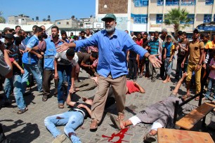 A man stands with dead and wounded Palestinians outside a UN school hit by an apparent Israeli airstrike in Rafah, in southern Gaza on Sunday.