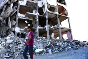 Feras Abu Inil, 13, walks past an apartment block that was all but destroyed during over a four week fight between Israel and Hamas in the northern Gaza strip on August 13.