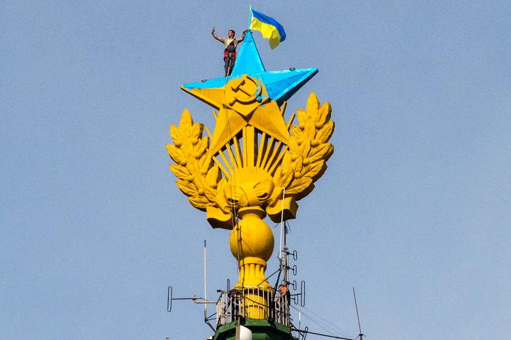 A worker takes a selfie before removing a yellow and blue Ukrainian flag attached by protesters atop a Stalin-era skyscraper in Moscow on Wednesday.