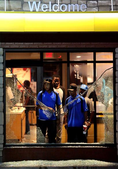 McDonald’s employees watch through a shattered window as riot police move in on protesters.