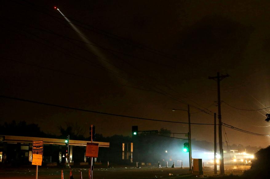 A police helicopter lights up the destroyed QuikTrip.