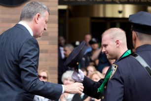 From hero to zero: Disgraced cop Eugene Donnelly is seen receiving a Combat Cross medal from Mayor de Blasio on June 10. Donnelly would later be arrested in the drunken assault of a Bronx woman whose home he is accused of breaking into.