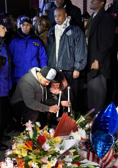 Lucy Ramos — the aunt of Rafael Ramos and a family member — attend a candlelight vigil for the slain officers.