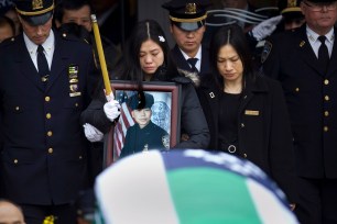 Widow Pei Xia Chen holds a photo of her slain husband Wenjian Liu as his casket departs the funeral home in Brooklyn on Sunday.