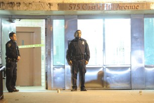 Police stand outside the Castle Hill housing project where three people were shot on Saturday night.