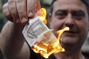 An anti-austerity protester burns a euro note during a demonstration outside the EU offices in Athens on June 28.