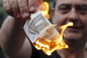 A protester burns a euro note during a demonstration outside the European Union In Athens on June 28.
