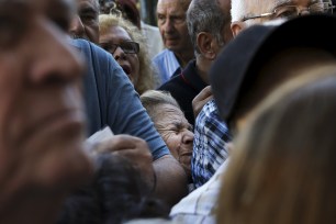 A pensioner is squeezed as she waits outside a bank in Athens on July 1.