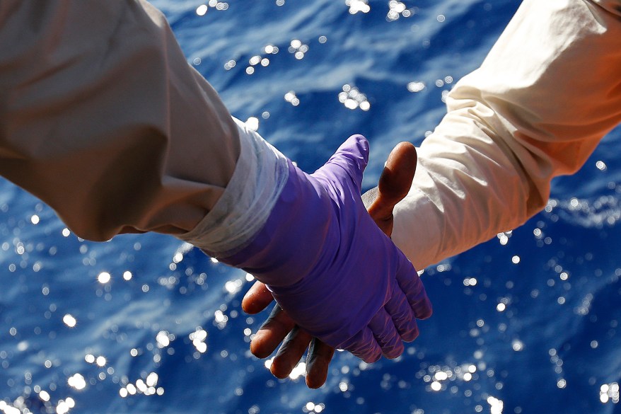 Migrants are helped to board on the Norwegian Siem Pilot ship during a migrant search and rescue mission off the Libyan Coast.