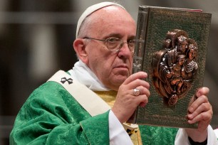 Pope Francis raises the book of the Gospels as he celebrates the opening Mass of the Synod of bishops, in St. Peter's Basilica at the Vatican on Sunday.