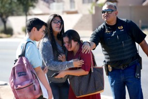 Students embrace after leaving campus, Friday, Feb. 12 in Glendale, Ariz. after two teens were shot Friday at Independence High School in the Phoenix suburb.