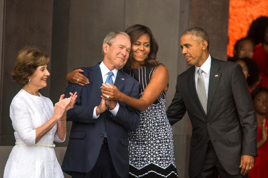 Michelle Obama hugs George W. Bush while Barack Obama and Laura Bush look on.