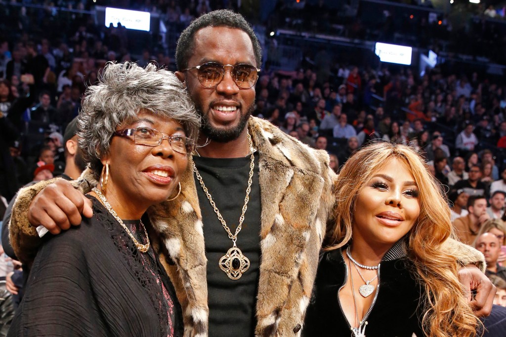 Violetta Wallace, left, mother of Biggie Smalls, also known as "The Notorious B.I.G.," poses for photographers with Sean "Diddy" Combs, center, and rapper Lil' Kim during a timeout in the second half of an NBA basketball game between the Brooklyn Nets and the New York Knicks, Sunday, March 12, 2017, in New York. 