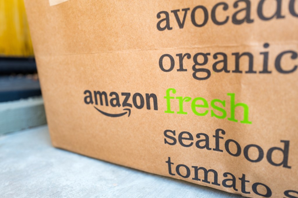 Brown paper tote for Amazon Fresh grocery delivery service, with Amazon logo and text listing groceries which may be ordered using the service, on the doorstep of a suburban home in the San Francisco Bay Area town of San Ramon, California, July 26, 2017. In June of 2017, Amazon announced that it would acquire the upscale grocery chain Whole Foods Market to expand its offerings in the grocery industry. (Photo via Smith Collection/Gado/Getty Images).