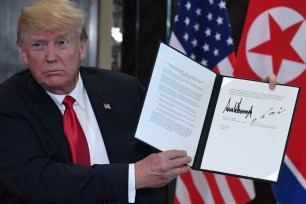 Donald Trump holds the signed document.