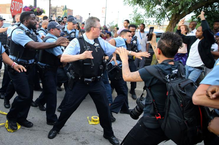 Members of the Chicago police department scuffle with an angry crowd at the scene of a police involved shooting.