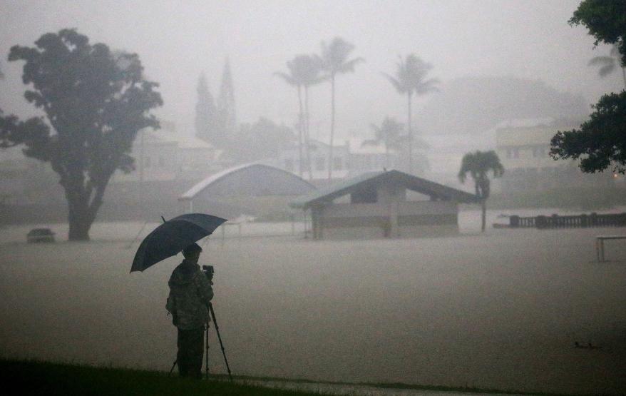 A man takes photos of floodwaters from Hurricane Lane rainfall.