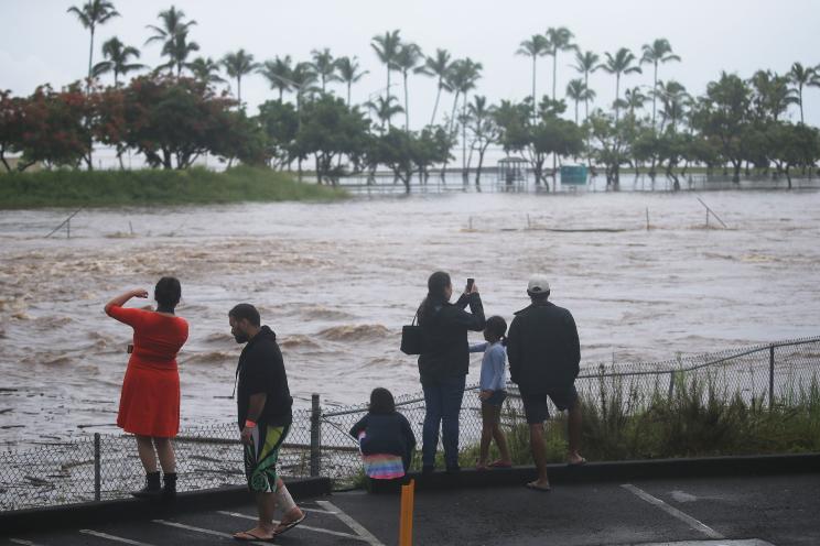 People gather to watch and take photos of floodwaters from Hurricane Lane rainfall on the Big Island