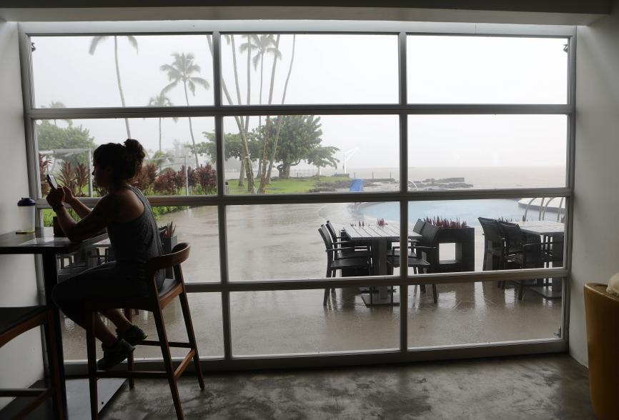 A woman sits in a hotel restaurant as rain falls on the Big Island.