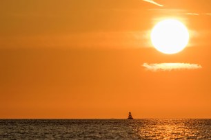 Image of large, hot sun setting on ocean.