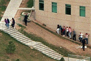 Police officers point weapons at a building as students take cover and flee the area outside Columbine High School in Littleton Colorado.