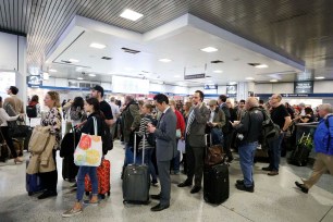 Travelers wait at Penn Station on Friday.